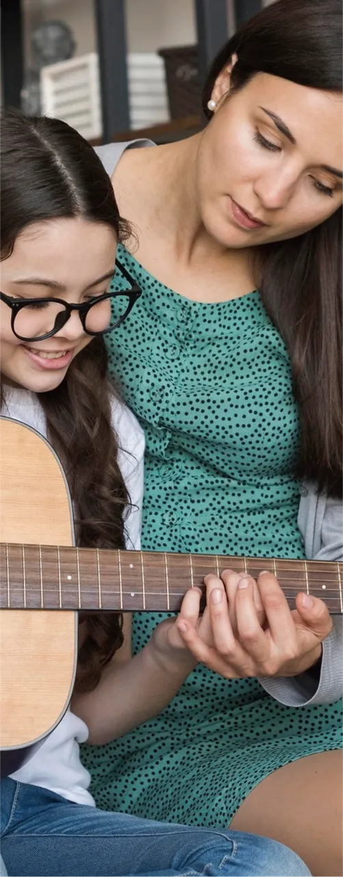 Adult guiding a child in playing guitar